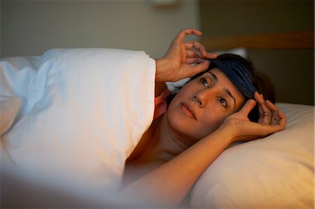 Mature woman putting on eye mask in hotel bed at night Stock Photo - Premium Royalty-Free, Code: 649-08548063