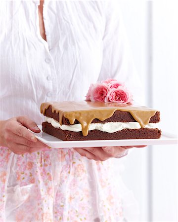 Woman holding chocolate sponge coffee cake decorated with flowers Stock Photo - Premium Royalty-Free, Code: 649-08548229