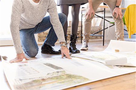 Low section of architects discussing blueprint on office floor Stock Photo - Premium Royalty-Free, Code: 649-08548447