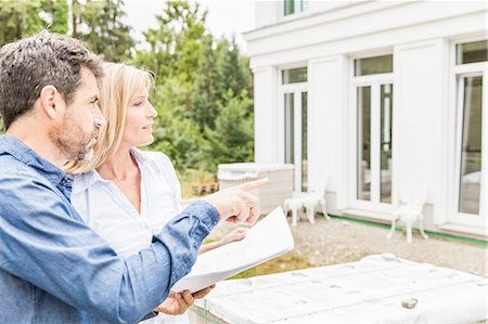 Architect showing homeowner plans for house exterior, looking away pointing Photographie de stock - Premium Libres de Droits, Code: 649-08548519