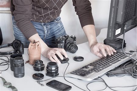 photographer - Photographer uploading photos from camera into computer in studio Stock Photo - Premium Royalty-Free, Code: 649-08548656