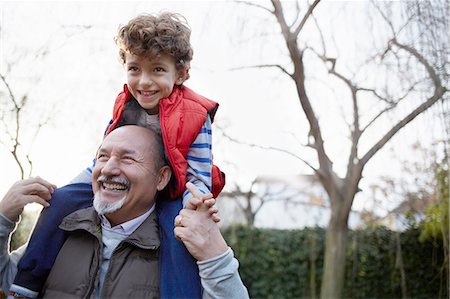 Mature man carrying grandson on shoulders smiling Stock Photo - Premium Royalty-Free, Code: 649-08548829