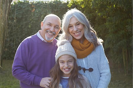 Granddaughter wearing bobble hat standing with grandparents looking at camera smiling Stock Photo - Premium Royalty-Free, Code: 649-08548955