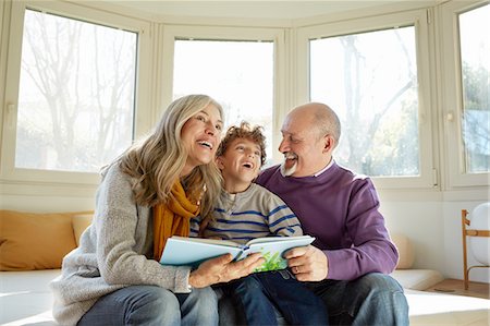 Grandparents on window seat reading book with grandson, smiling Stock Photo - Premium Royalty-Free, Code: 649-08548966