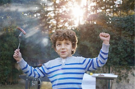 processed meats - Boy arms raised holding sausage on fork smiling Stock Photo - Premium Royalty-Free, Code: 649-08548975