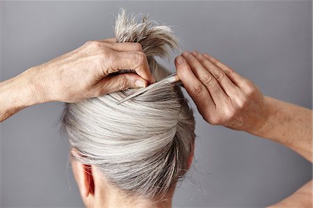 Rear view of woman styling gray hair into bun Foto de stock - Royalty Free Premium, Número: 649-08549356