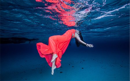 dramatizing - Woman in red floating near surface of ocean Photographie de stock - Premium Libres de Droits, Code: 649-08543119