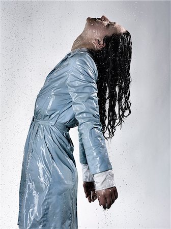 Side view of woman wearing raincoat drenched in water throwing back head Photographie de stock - Premium Libres de Droits, Code: 649-08543280