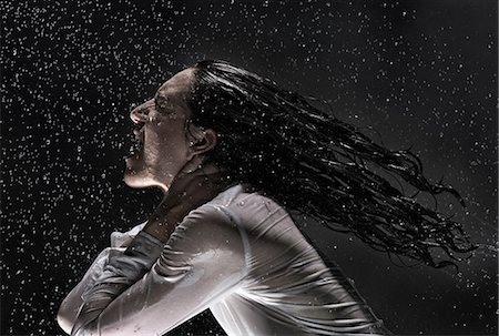 Side view of woman wearing white shirt drenched in rain throwing back hair Photographie de stock - Premium Libres de Droits, Code: 649-08543282