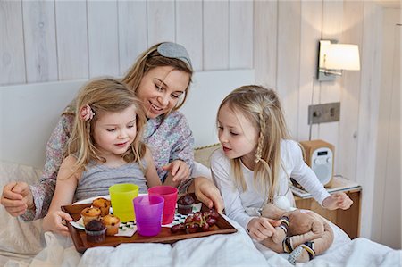 Mother and daughters having breakfast in bed Stock Photo - Premium Royalty-Free, Code: 649-08543572