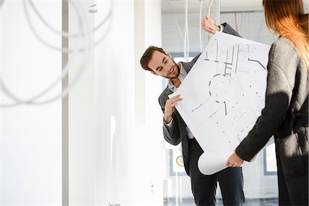 Architect showing blue print to client in new office building Stock Photo - Premium Royalty-Free, Code: 649-08543679