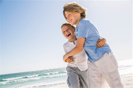 Brothers on beach hugging looking away smiling Stock Photo - Premium Royalty-Free, Code: 649-08543776