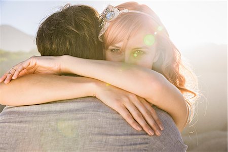 simsearch:649-08543866,k - View over shoulder of woman hugging man, looking at camera Stock Photo - Premium Royalty-Free, Code: 649-08543868