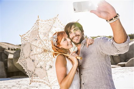 simsearch:649-08543866,k - Couple on beach holding lace umbrella using smartphone to take selfie Photographie de stock - Premium Libres de Droits, Code: 649-08543886