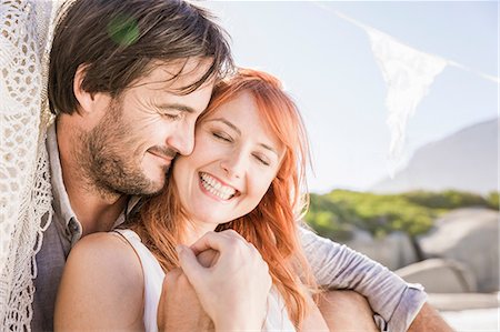 simsearch:649-08543884,k - Head and shoulders of couple sitting hugging holding hands smiling Fotografie stock - Premium Royalty-Free, Codice: 649-08543891
