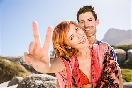 simsearch:649-08543928,k - Portrait of couple outdoors, young woman making peace sign, smiling Stockbilder - Premium RF Lizenzfrei, Bildnummer: 649-08543914