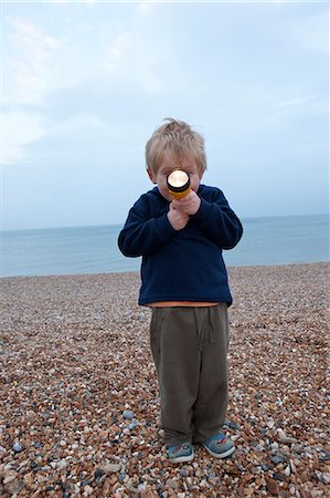 Boy with torch on pebble beach Stock Photo - Premium Royalty-Free, Code: 649-08564122