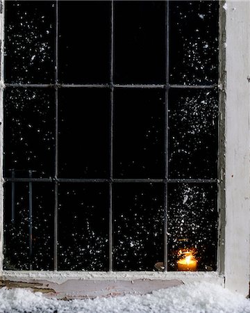 snowy night at home - Candle burning in snow covered house window Stock Photo - Premium Royalty-Free, Code: 649-08565409