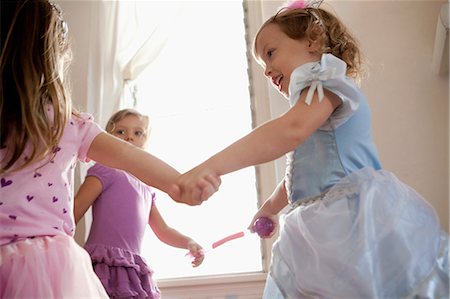 Three young girls in party dress holding hands and dancing Foto de stock - Sin royalties Premium, Código: 649-08565509