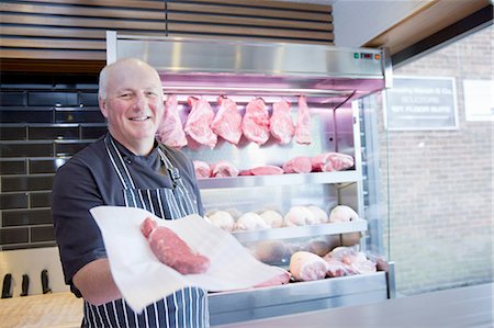 Portrait of butcher holding steak in butchers shop Stock Photo - Premium Royalty-Free, Code: 649-08565934