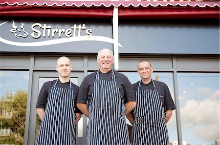 Portrait of three male butchers outside butchers shop Fotografie stock - Premium Royalty-Free, Codice: 649-08565932