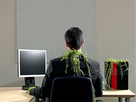 Man sitting by desk, plants growing Stock Photo - Premium Royalty-Free, Code: 649-08560181