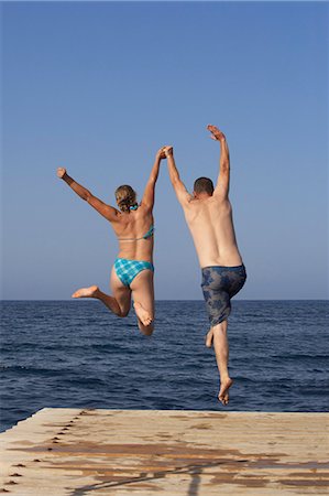 Man and Woman jumping into sea from pier Stock Photo - Premium Royalty-Free, Code: 649-08560422