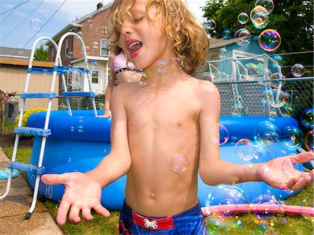 Boy playing with bubbles in garden, paddling pool in background Photographie de stock - Premium Libres de Droits, Code: 649-08563350