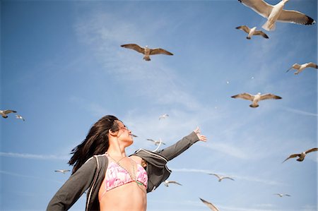 Young woman reaching towards gulls Photographie de stock - Premium Libres de Droits, Code: 649-08563621