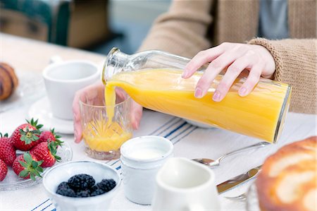 simsearch:689-03130324,k - Cropped view of woman pouring orange juice from bottle into glass Stock Photo - Premium Royalty-Free, Code: 649-08576325