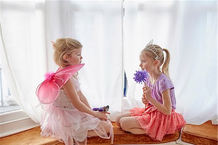 Two young girls, in fancy dress, sitting face to face Stock Photo - Premium Royalty-Free, Code: 649-08576375