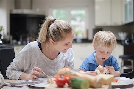 simsearch:649-08576682,k - Mother and son sitting at table eating meal together Fotografie stock - Premium Royalty-Free, Codice: 649-08576671