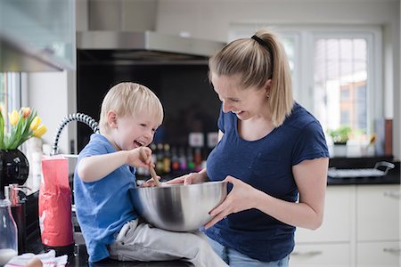 simsearch:649-08576682,k - Mother and son fooling around whilst baking, stirring mixture in mixing bowl Fotografie stock - Premium Royalty-Free, Codice: 649-08576684