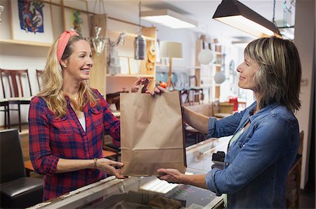 shop clerk woman - Shop assistant handing shopper shopping bag Stock Photo - Premium Royalty-Free, Code: 649-08576901