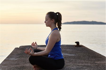 simsearch:614-06814385,k - Young woman sitting on pier, in yoga position, at sunset Photographie de stock - Premium Libres de Droits, Code: 649-08576999