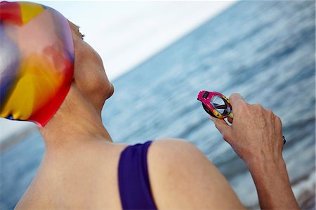 simsearch:649-08577001,k - Mature woman wearing swimming costume, swimming hat and holding swimming goggles, standing beside the sea, rear view Fotografie stock - Premium Royalty-Free, Codice: 649-08577009