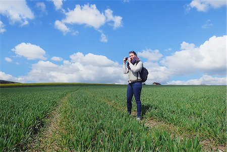 simsearch:649-08895049,k - Young woman standing in field, taking photograph of landscape Photographie de stock - Premium Libres de Droits, Code: 649-08577095