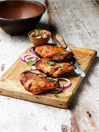 Barbecued tandoori chicken thighs with salad on chopping board Photographie de stock - Premium Libres de Droits, Code: 649-08577143