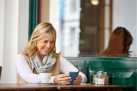 simsearch:614-08544994,k - Mature woman reading smartphone text at sidewalk cafe table Foto de stock - Sin royalties Premium, Código: 649-08577189