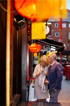quartiere cinese - Mature couple reading restaurant menu in China Town at dusk, London, UK Fotografie stock - Premium Royalty-Free, Codice: 649-08577217