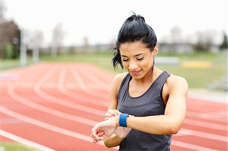 simsearch:649-08577265,k - Young woman on running track, checking watch Stock Photo - Premium Royalty-Free, Code: 649-08577261