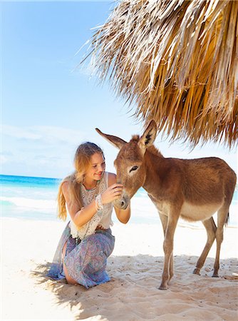photos of donkeys on the beach - Young woman kneeling to pet donkey on beach, Dominican Republic, The Caribbean Stock Photo - Premium Royalty-Free, Code: 649-08577349