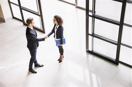 saludo - High angle view of businesswoman and man shaking hands at  office entrance Foto de stock - Sin royalties Premium, Código: 649-08577373