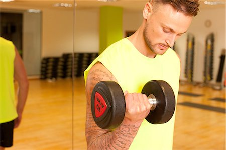 simsearch:649-07585504,k - Tattooed man at gym lifting dumbbells Stockbilder - Premium RF Lizenzfrei, Bildnummer: 649-08577461