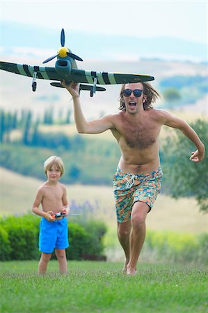 simsearch:649-08125829,k - Father and son flying remote control plane, outdoors Foto de stock - Royalty Free Premium, Número: 649-08577497