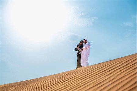 simsearch:649-08577606,k - Middle eastern couple wearing traditional clothes taking smartphone selfie on desert dune, Dubai, United Arab Emirates Stock Photo - Premium Royalty-Free, Code: 649-08577586