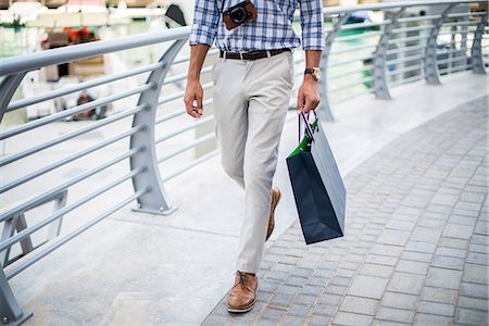 rich people outdoor - Waist down view of young man strolling on waterfront carrying shopping bag, Dubai, United Arab Emirates Stock Photo - Premium Royalty-Free, Code: 649-08577617