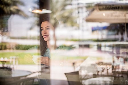Happy woman behind reflective cafe window, Dubai, United Arab Emirates Stock Photo - Premium Royalty-Free, Code: 649-08577621