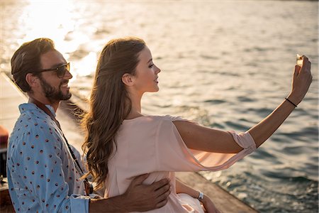 Romantic couple taking smartphone selfie on boat at Dubai marina, United Arab Emirates Stock Photo - Premium Royalty-Free, Code: 649-08577646