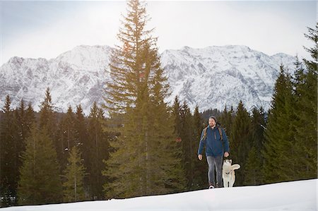 Young man walking uphill with husky in snow covered landscape, Elmau, Bavaria, Germany Stock Photo - Premium Royalty-Free, Code: 649-08577735